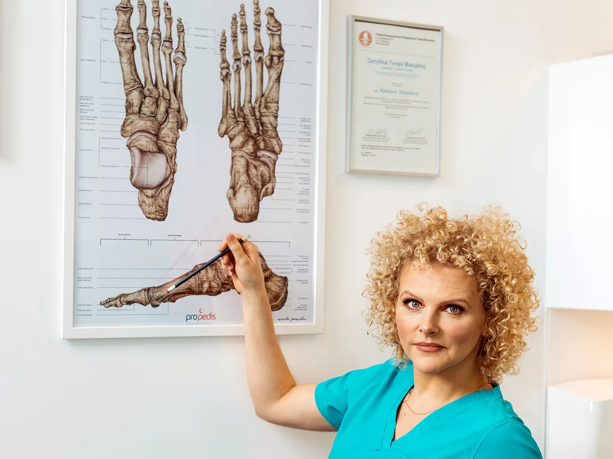 Joanna Stodolna-Tukendorf wskazuje planszę z anatomią kości stopy