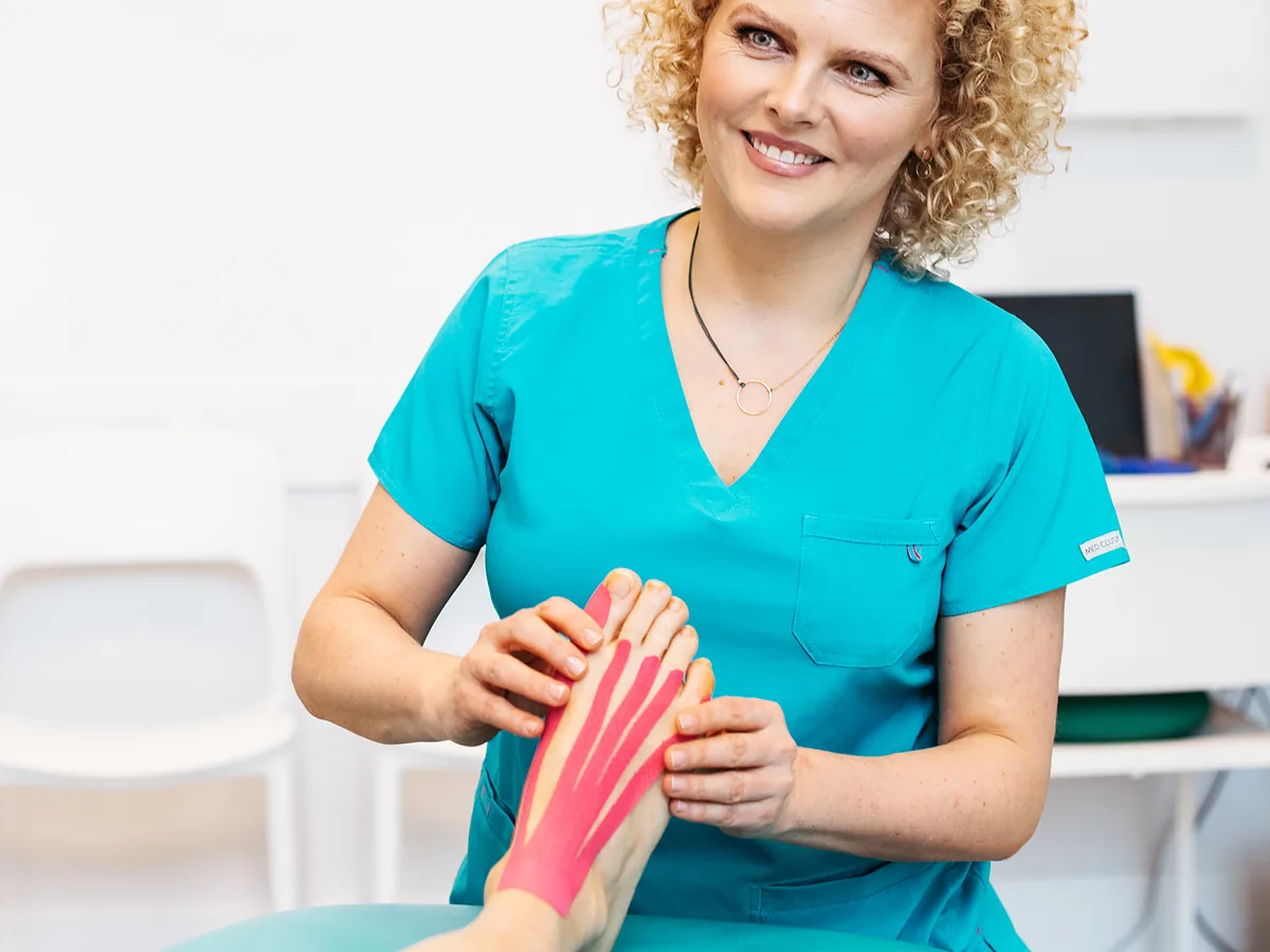 Joanna Stodolna-Tukendorf z taśmą do kinesiotapingu przy nodze pacjenta