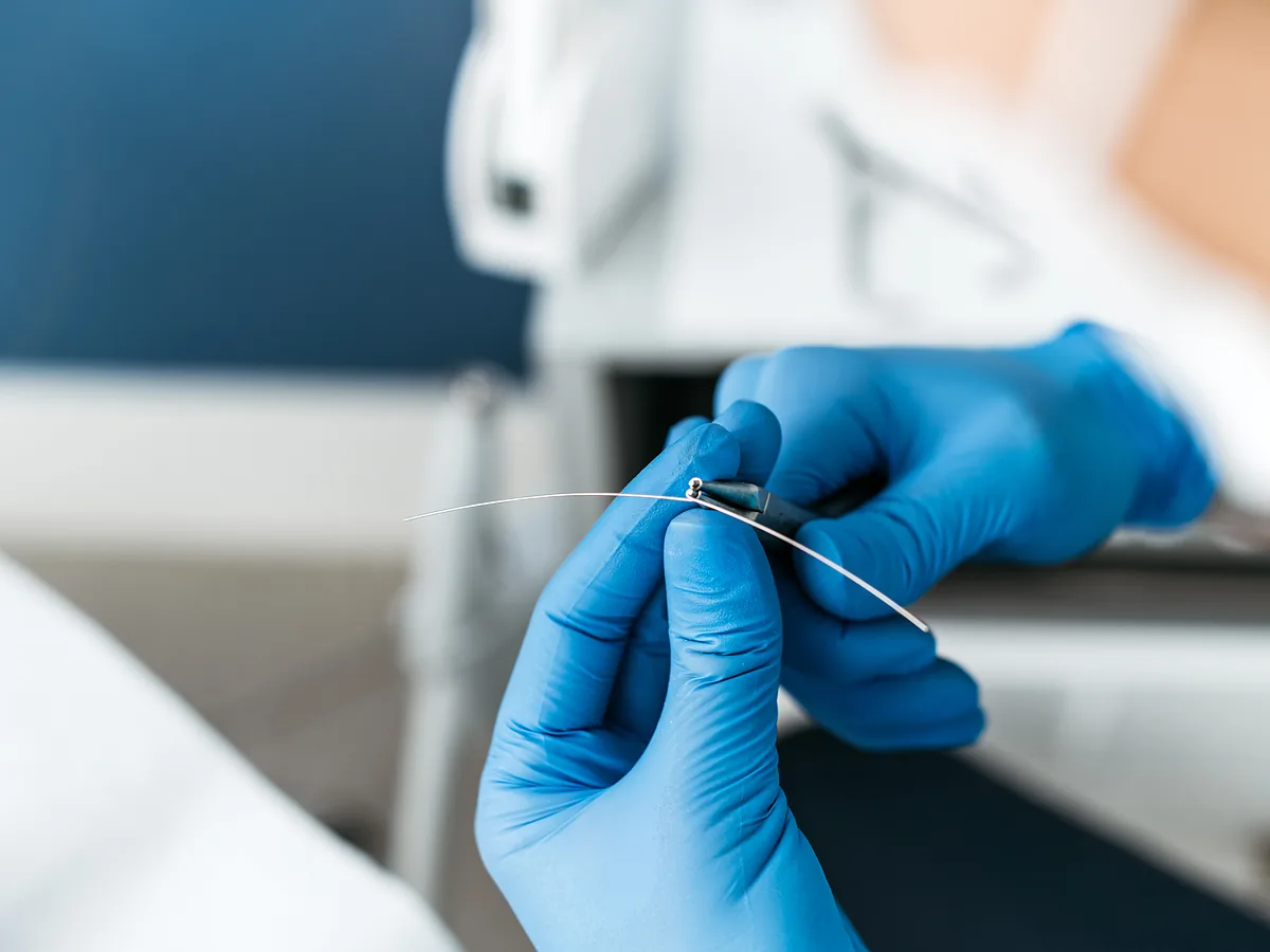 Podolog FootMedica w rękawiczkach formuje drut klamry
